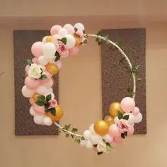 A festive garland of gold, pink, blush, and white latex balloons twisted together, adorned with floral accents. This garland is perfect for a baby shower, graduation party, or any celebration in NYC.
