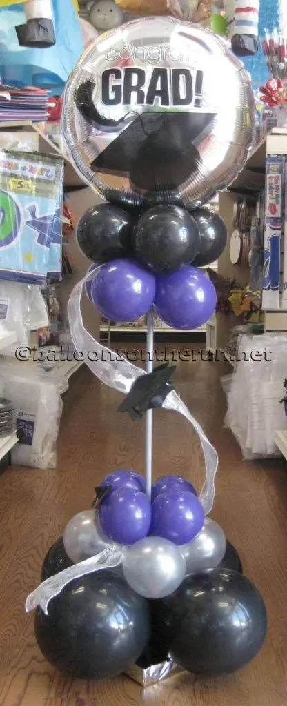 Column of small purple, black, and grey balloons with a big customized silver graduation balloon delivered by Balloons Lane in NYC