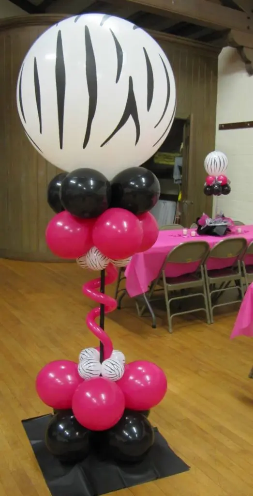 Column of small pink, black, and white balloons with a big customized white balloon with black lines by Balloons Lane in NJ