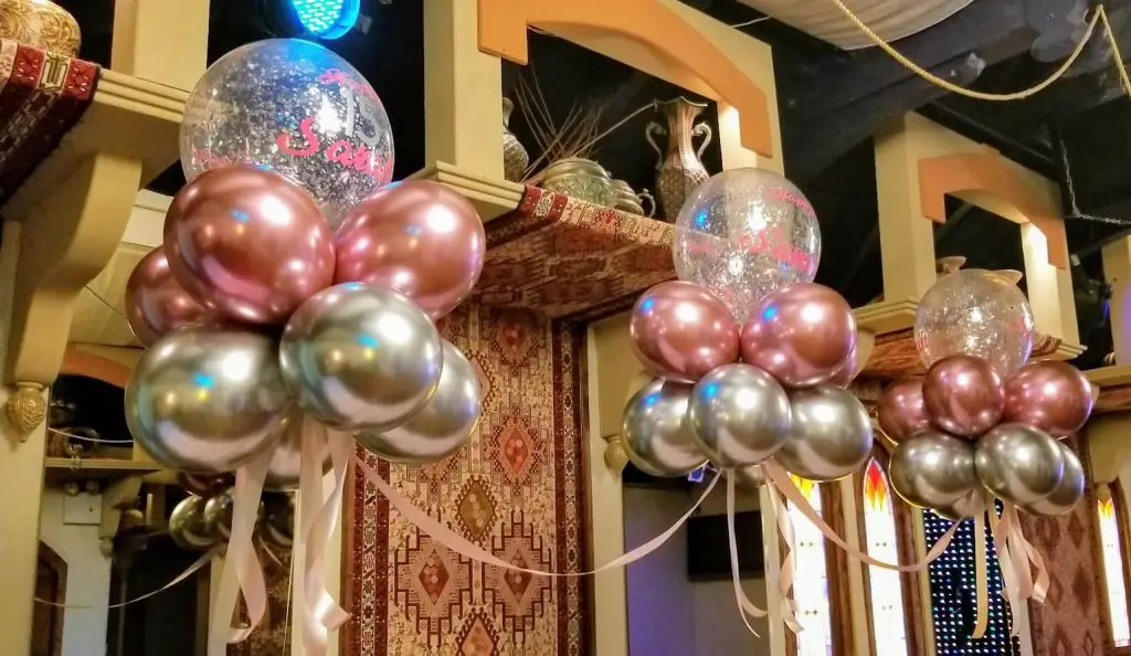 A dazzling arch made of Chrome Pink, Chrome Silver, and Clear balloons filled with Silver Confetti, perfect for adding a touch of glamour and elegance to a Sweet 16 girl's birthday party.