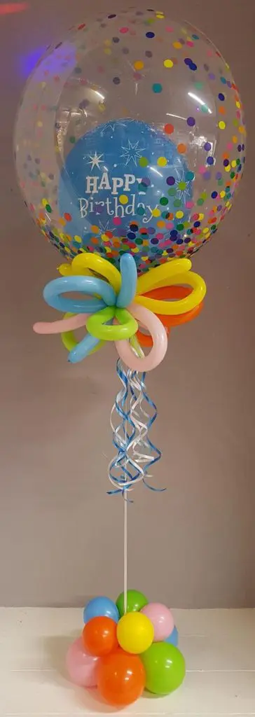 Clear balloon with colorful polka dot and insider balloon with string and orange, green, pink, and light blue balloons centerpiece