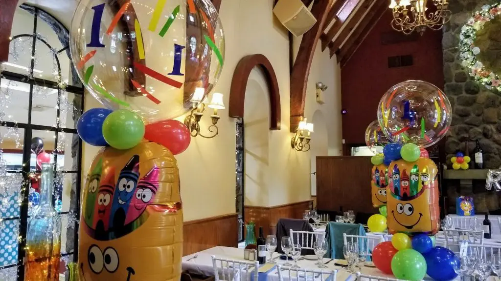 Round personalized centerpieces featuring a Creon theme, created by Balloons Lane in Brooklyn. The centerpieces are decorated with colorful balloons.