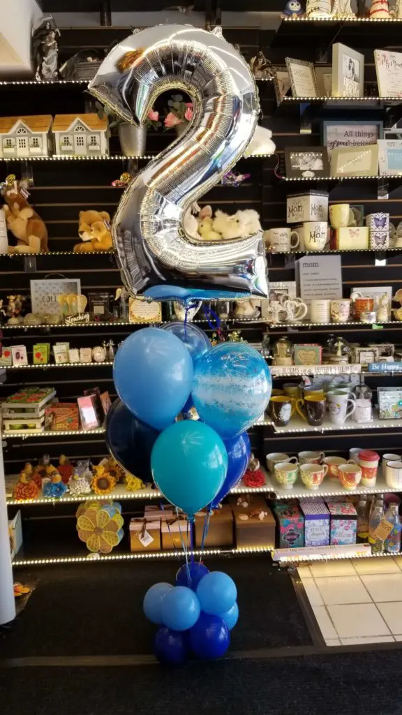 A balloon column featuring purple, azure, dark blue, and silver balloons, along with number balloons in silver, arranged in New York City.