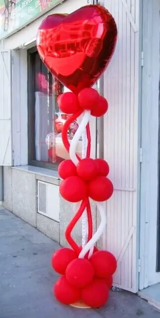 Red and white balloons with a big heart mylar on a stand for Valentine's Day decor.