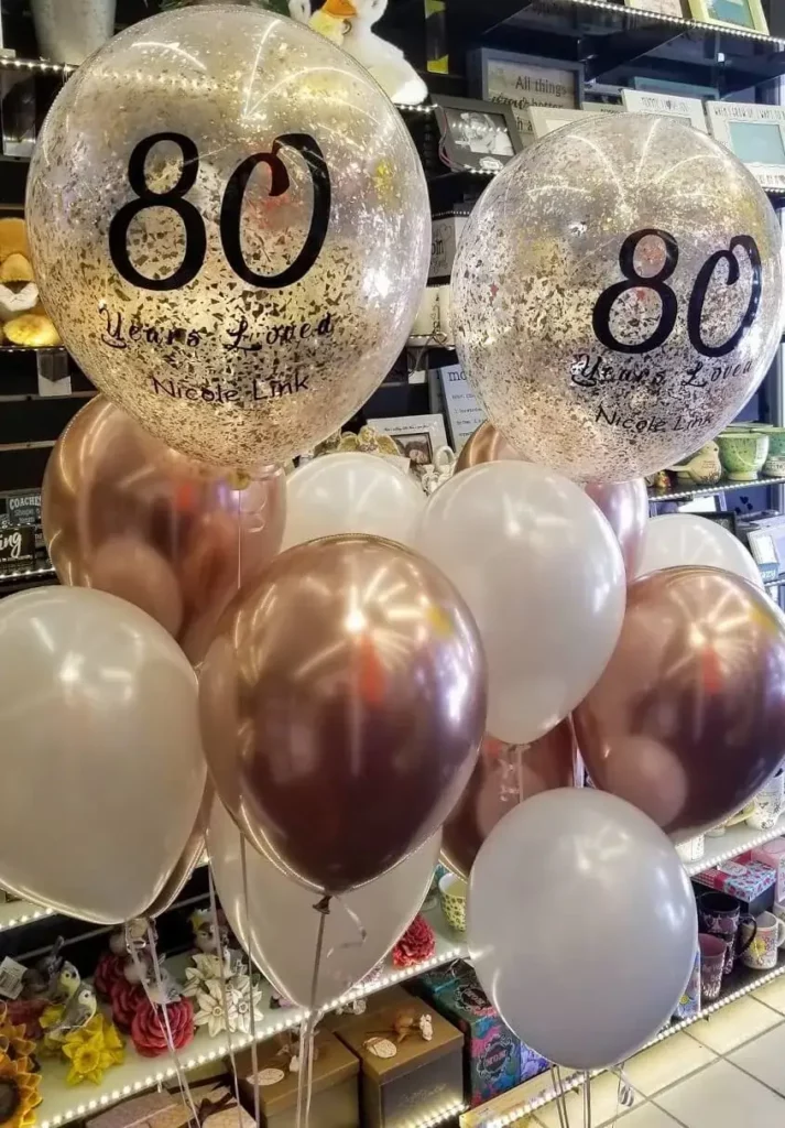 A beautiful balloon arrangement featuring rose gold and pearl white balloons, perfect for an 80th birthday celebration.
