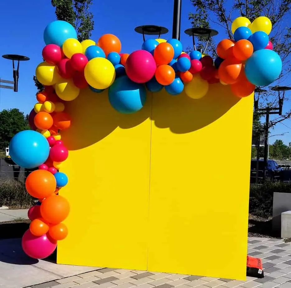 A vibrant and colorful balloon arch in bright shades of blue, red, orange, and yellow, perfect for adding a festive touch to any event.